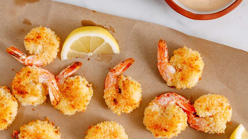 Air fried popcorn shrimp on butcher paper with a wedge of lemon