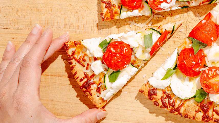 Reheated pizza topped with tomatoes, goat cheese, and scallion